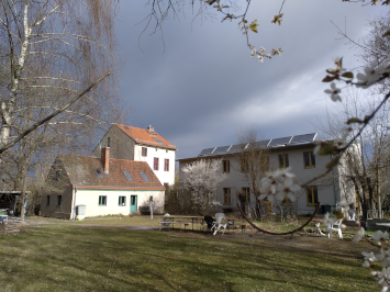 Blick auf die drei Häuser mit dramatischen Wolken und blühenden Bäumen